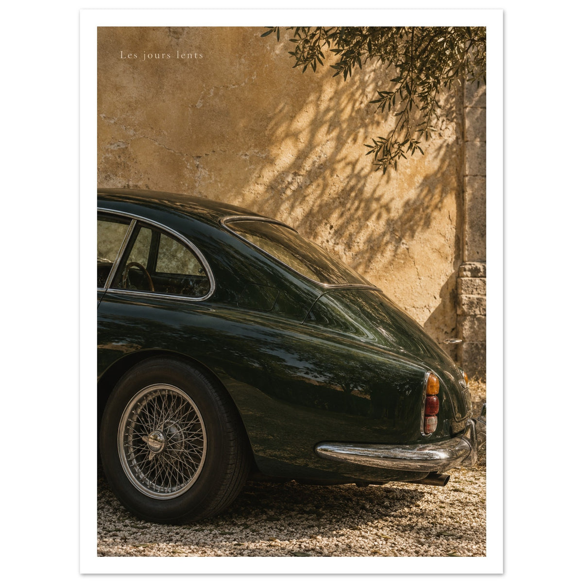 Deep green classic car beside a sunlit ochre wall with leafy shadows as an unframed poster.