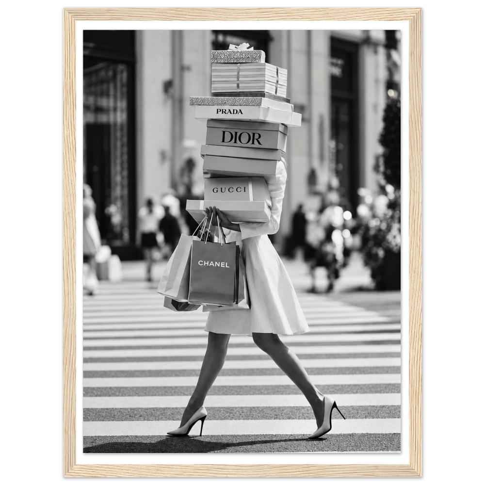 Woman crossing a street in heels carrying a tall stack of shopping boxes in a natural wood frame.