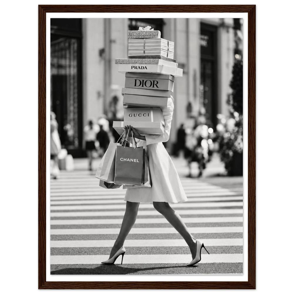 Woman crossing a street in heels carrying a tall stack of shopping boxes in a dark wood frame.