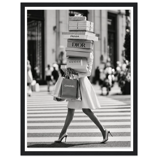 Woman crossing a street in heels carrying a tall stack of shopping boxes in a black frame.