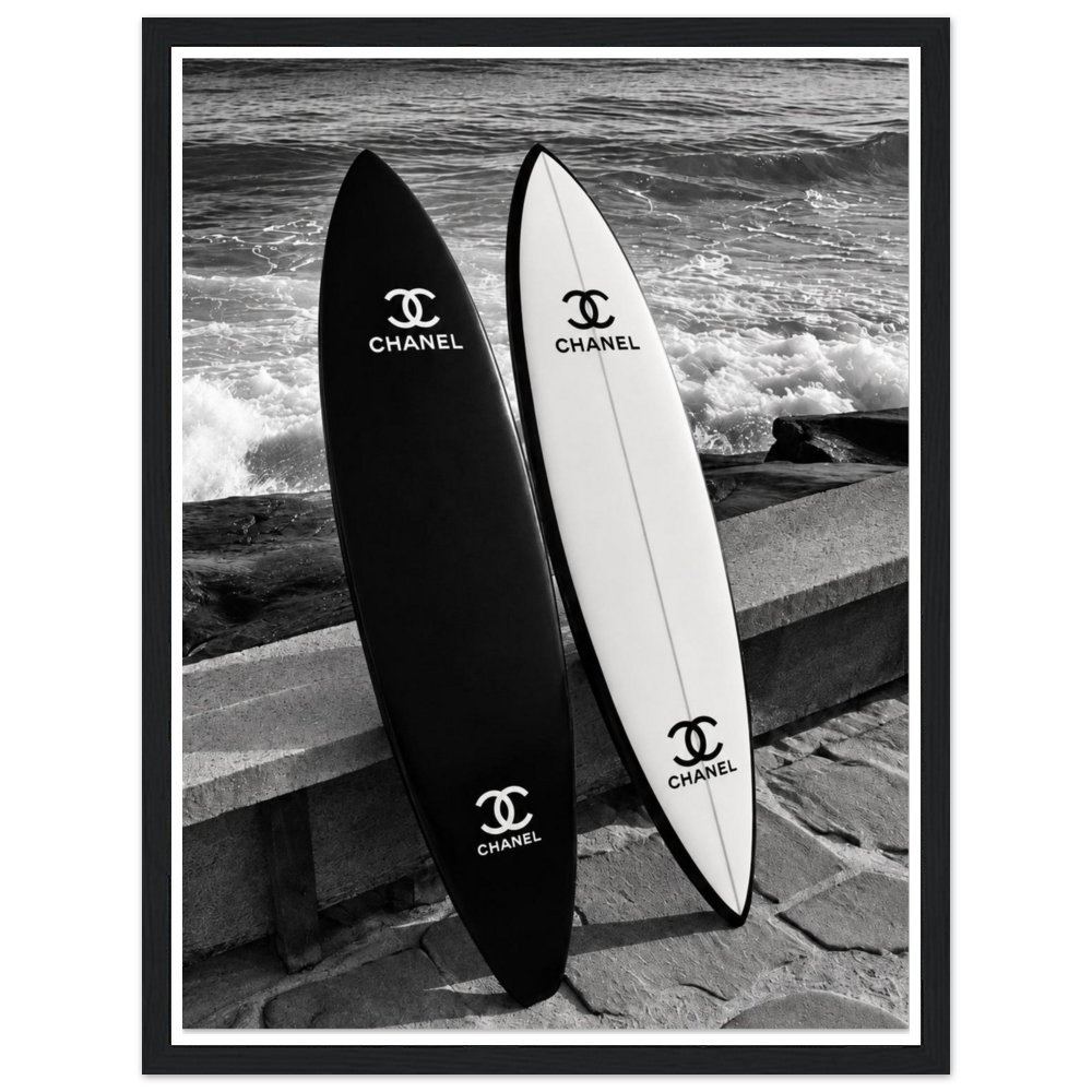 Black and white surfboards leaning against a sea wall beside the waves in a black frame.